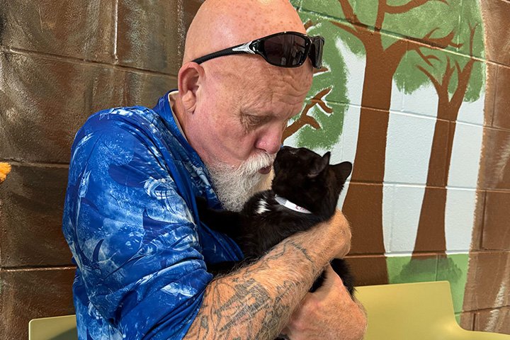 man cuddling a black cat
