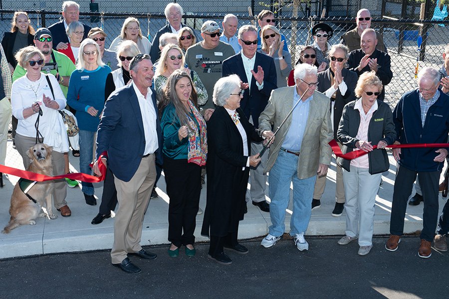 group of people smiling and laughing as the cut a large red ribbon at the Suncoast Humane Society Soderberg Campus, January 9, 2025