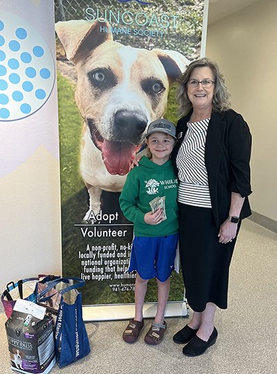 young Mason with his generous gift of toys, puppy pads, and cash, standing with Suncoast Humane Society's Christine Varcoe